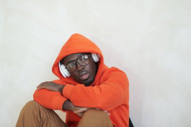 Turuncu kapüşonlu ve kulaklıklı yakışıklı Afro-Amerikan 'ın yatay portresi.