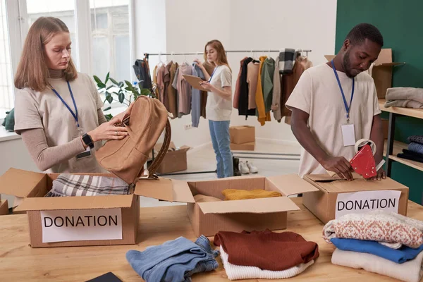 stock image Group of active people working in clothes charity organization sorting and packing items for donation