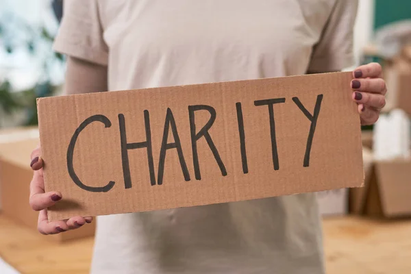 stock image Medium section shot of unrecognizable woman wearing beige T-shirt holding cardboard sign with Charity word written on it