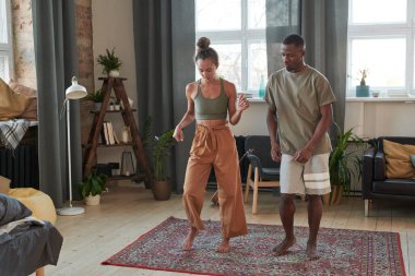 Afro-Amerikalı erkek ve beyaz kadın sabahlarını evde birlikte dans ederek geçiriyorlar.