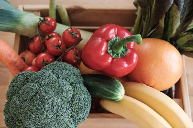 Greyfurt, muz, dolma biber, vişneli domates ve brokoli gibi sağlıklı yiyeceklerin tam üstünde.