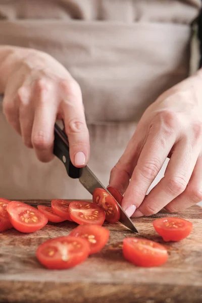 stock image Close-up of unrecognizable woman cutting cherry tomato with knife on wooden board