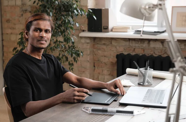 Muotokuva Hymyilevä Nuori Intialainen Suunnittelija Mustassa Paidassa Istuu Pöydällä Käyttää — kuvapankkivalokuva