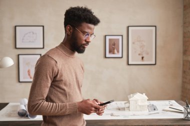 Sakallı genç Afro-Amerikan mimar müşteriye planlı ve mesajlı bir şekilde masanın karşısında duruyor.
