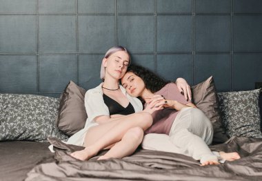 Saten keten kumaşlarla yatakta uzanan güzel lezbiyen kadınlar.