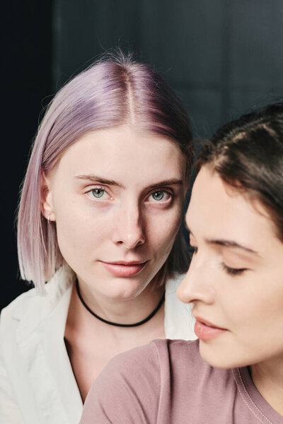 Portrait of content young Caucasian lesbians posing together against piled wall