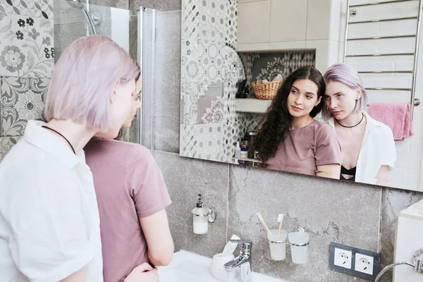 stock image Beautiful lesbian girls embracing in front of mirror in bathroom with piles