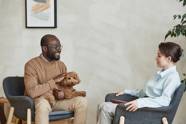 Sonriente Joven Afroamericano Acariciando Perro Mientras Habla Con Psicólogo Durante — Foto de Stock