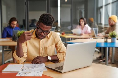 Düşünceli Siyah Strateji Yöneticisi çalışma alanında oturup belgeleri inceliyor