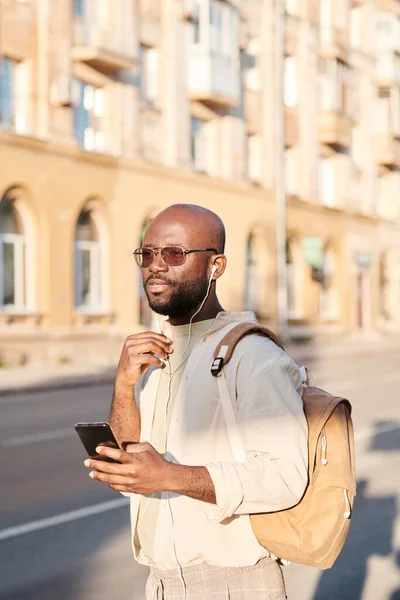 在街上用耳机听音乐的年轻的非洲裔美国人沉思的秃头男子 — 图库照片