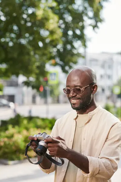 Hymyilevä Nuori Afroamerikkalainen Valokuvaaja Silmälaseissa Katselemassa Kuvia Kameran Edessä Ulkona — kuvapankkivalokuva