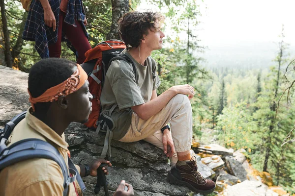 一群年轻的多民族徒步旅行者站在高山上的大石头上 欣赏着周围美丽的自然风光 — 图库照片