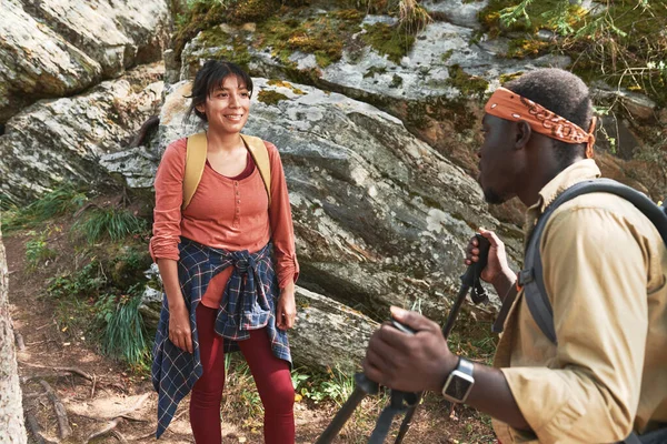 岩だらけの山の上に立っている混合人種の女性を笑顔で話す極を歩くアフリカ系アメリカ人の男 — ストック写真