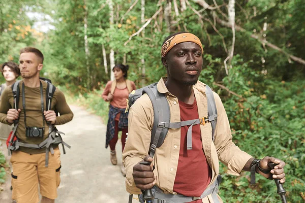 若者のグループ多民族の観光客が一緒に森の中を歩いて停止場所を見つける — ストック写真