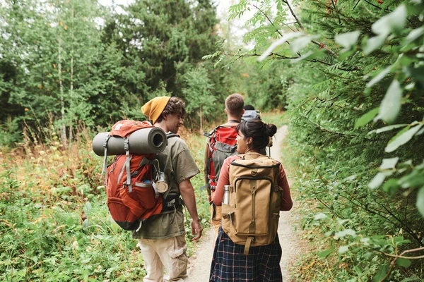 バックパックを背負った若者が森の中を歩きながらハイキング中に話す姿 — ストック写真