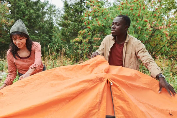 积极的多族裔年轻夫妇在户外搭帐篷 — 图库照片