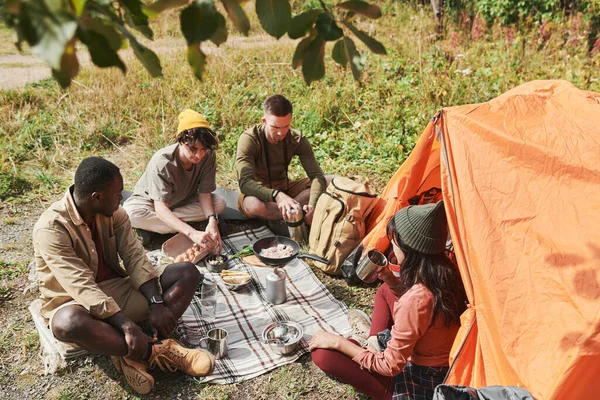 一群年轻的多族裔人坐在地上 在露营时吃午饭 — 图库照片