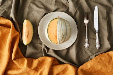 Tabaktaki sulu karpuz ve çatal ve bıçakla buruşuk kumaş dilimlerinin tam üstünde.