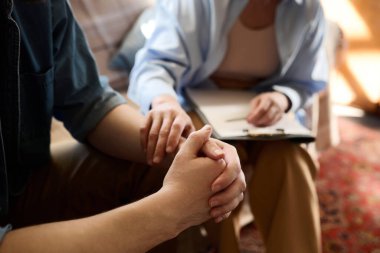 Ofiste hastasını destekleyen psikoloğun yakın çekimi sırasında elini tutuyor.