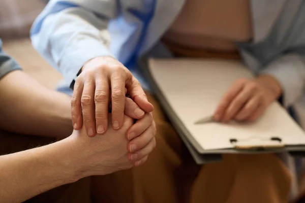 Terapistin seansta hastasını destekleyip elini tutup onunla konuştuğu yakın plan.
