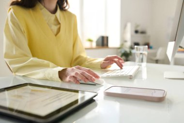 Ofisteki iş yerinde bilgisayar başında çalışan genç bir kadının yakın çekimi.