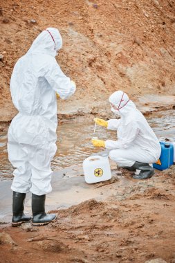 Koruma altındaki ekologlar tehlikeli bölgede kirlenmiş su örneği alırken pipet kullanıyorlar.