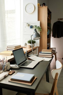 Elektrikli lamba, kitap, eskiz defteri, dizüstü bilgisayar ve ofis malzemelerinden oluşan modern iş yeri.