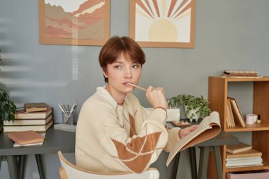 Eskiz defterindeki notları düşünürken kısa saçlı, ciddi derecede düşünceli beyaz kız.