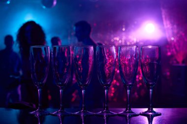 Champagne flutes in row on bar counter in nightclub clipart