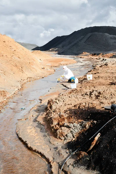 Szennyezéskutató Folyónál Guggoló Védőmunkaruhában Vízmintát Vesz Miközben Veszélyes Mérgező Területen — Stock Fotó