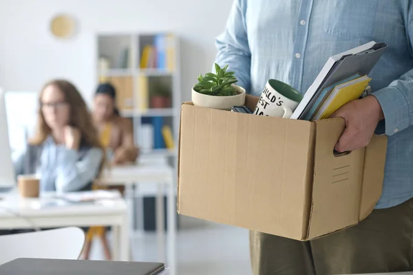 Close-up of businessman standing with box with office stuff after his layoff