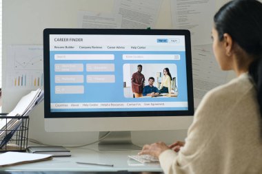 İş yerinde bilgisayarla otururken genç bir iş kadınının özgeçmişini web sitesine yüklemesi.