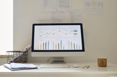 Ofisteki masada duran ekranda mali grafikleri olan bilgisayar