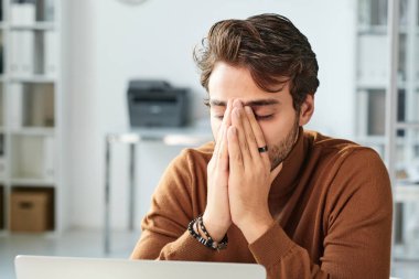 Kafası karışmış genç bir ortadoğu yöneticisi, sakalları gerilmiş ve yüzünü ellerle kapatmış.