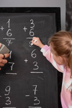 Okulda sayıları sayarken tahtaya matematik çözeltisi yazan kız