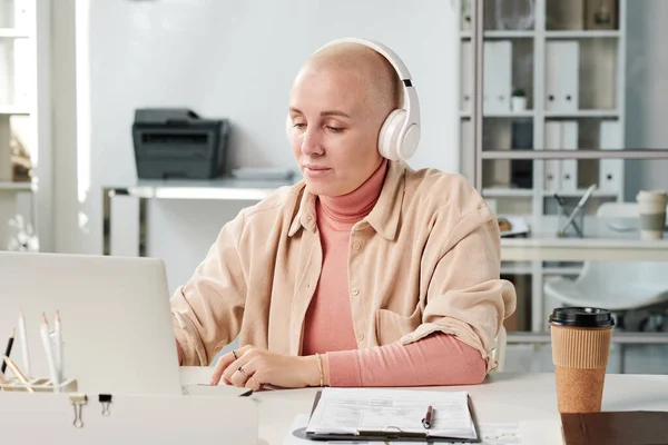 Zawartość Młoda Kobieta Biurowa Słuchawkach Bezprzewodowych Słuchających Muzyki Podczas Pracy — Zdjęcie stockowe