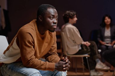 Genç siyahi bir adamın grup psikoterapisine katılışının yatay görüntüsü.