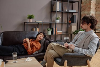 Depresyondaki genç bir kadınla psikanaliz yapan modern profesyonel psikoterapistin yatay çekimi.