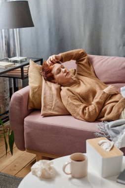 Dikey yüksek açı görüntüsü olan bir kadın ilaç aldıktan sonra evinde kanepede yatıyor.