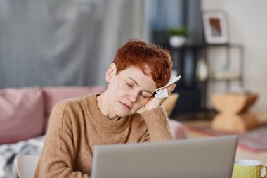 Olgun, beyaz bir kadının ateş ve baş ağrısının baş üstünde yatay olarak çekilmiş fotoğrafı.