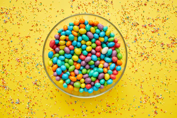 Glassy Bowl Full Colorful Sweet Beans Yellow Background Splattering Sprinkles — Stock Photo, Image