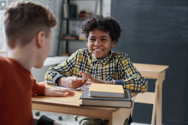 Usmívající Afroameričan Školák Mluvit Svým Spolužákem Zatímco Oni Sedí Stolem — Stock fotografie