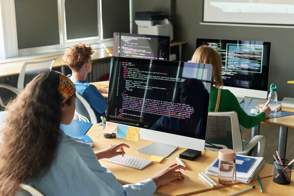 Группа студентов, пишущих компьютерные коды во время урока в школе