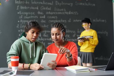 Sınıfta masa başında otururken, çalışma odalarında tablet kullanan Afrikalı Amerikalı öğrenciler.