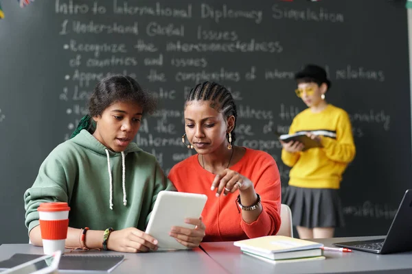 Sınıfta masa başında otururken, çalışma odalarında tablet kullanan Afrikalı Amerikalı öğrenciler.