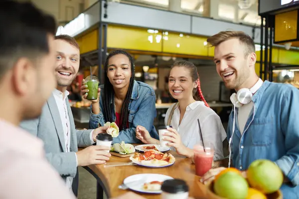 Group of excited young multi-ethnic friends spending time on food court and chatting together