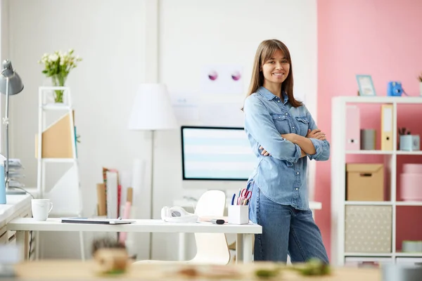 Portrait of smiling confident young female employee of design company standing in modern feminine office
