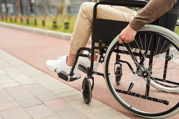 Bej kotlu, modern tekerlekli sandalyede yürümekte zorlanan, tanınmayan bir adamın yakın çekimi.