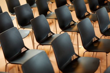 Seminer ve eğitim sınıfı için bekleme salonunda duran boş siyah plastik sandalyelerin arkaplan resmi