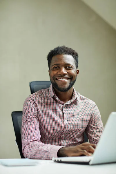 ポジティブな若いひげ付きアフリカ系アメリカ人のItエンジニアの肖像画が現代のオフィスでラップトップの前に座っている — ストック写真